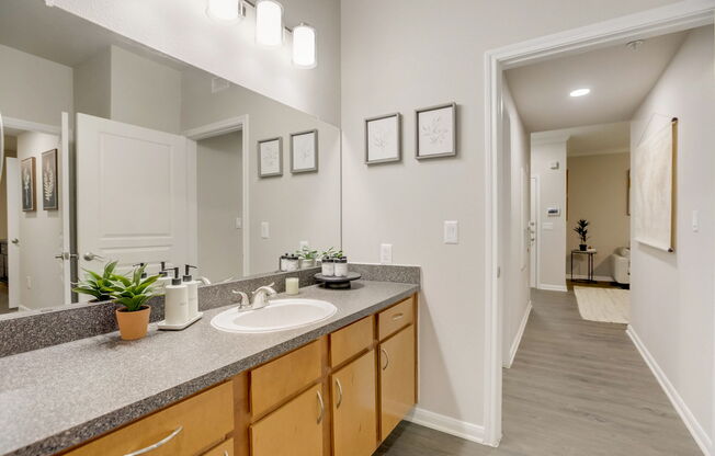 A bathroom with a sink, mirror, and wooden cabinets.