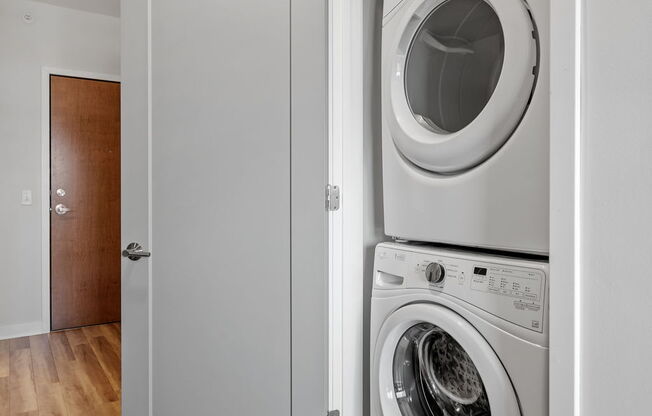 A white washing machine is in a cabinet in a room with wooden floors.
