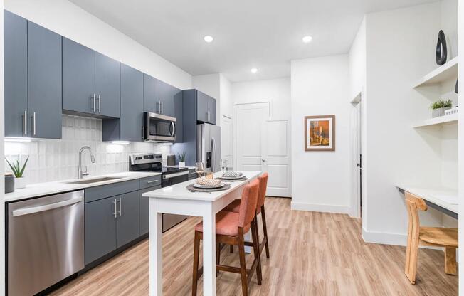 Savor the details at Modera Garden Oaks. Enjoy a modern kitchen with a chrome Symmons pull-down spray faucet and a chic tile backsplash that adds a touch of elegance to your everyday cooking.