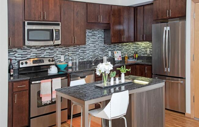 A kitchen with a table and chairs in front of a refrigerator.