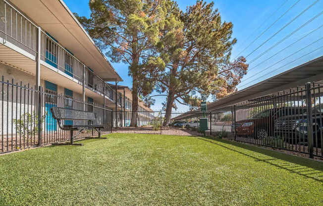 A grassy area in front of a building with a tree and a fence.