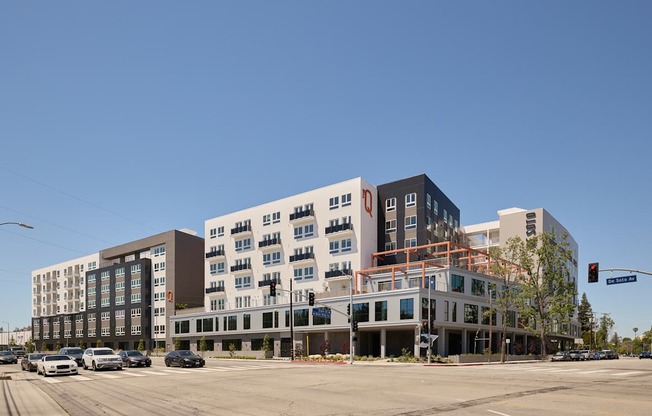 A modern multi-story building with a parking lot in front.