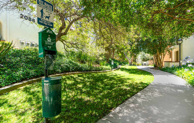 A sign on a pole in a park indicates a dog walking area.