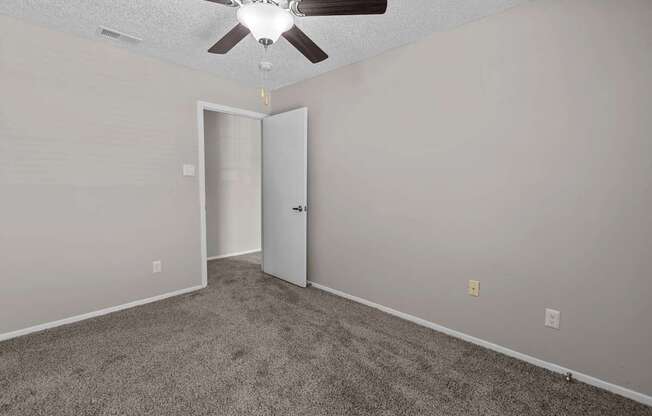 A room with a ceiling fan and carpeted floor.