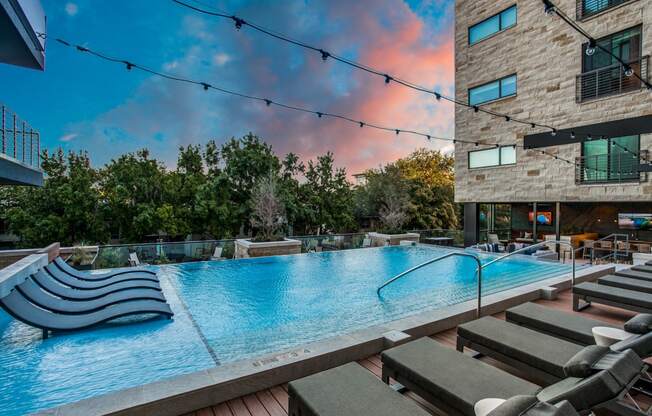 a large pool with lounge chairs and a building in the background