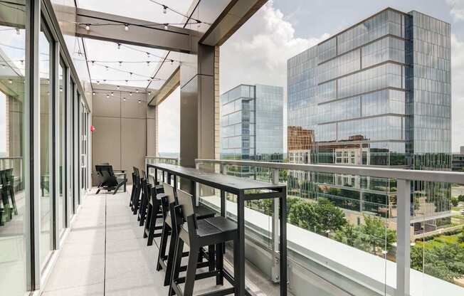 A balcony with a table and chairs overlooking a cityscape.