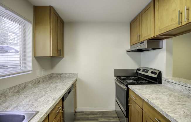 a kitchen with wooden cabinets and granite countertops at Park 210 Apartment Homes, Edmonds, Washington