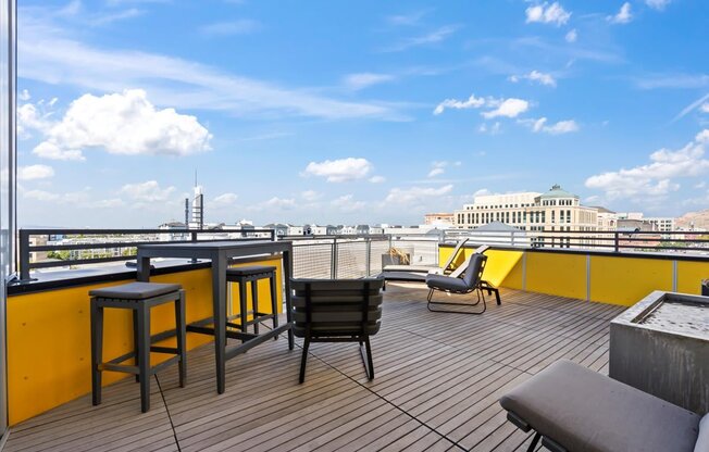 A balcony with a table and chairs overlooking a cityscape.