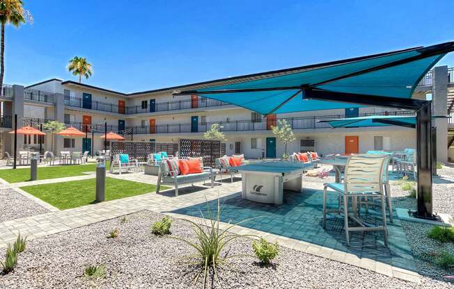A pool area with a table and chairs under a shade sail.