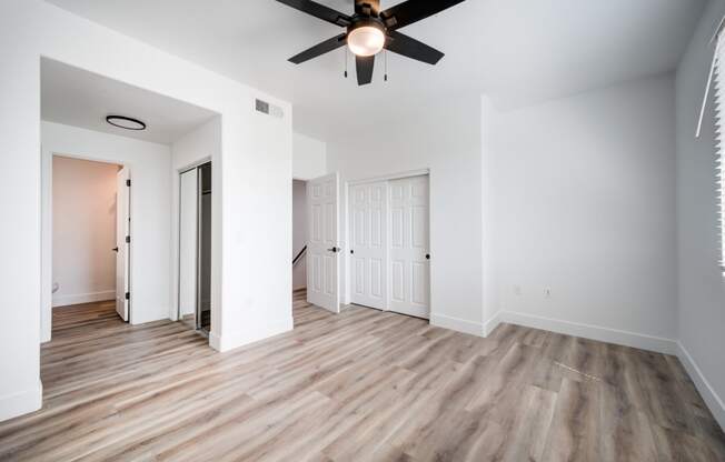an empty living room with white walls and a ceiling fan