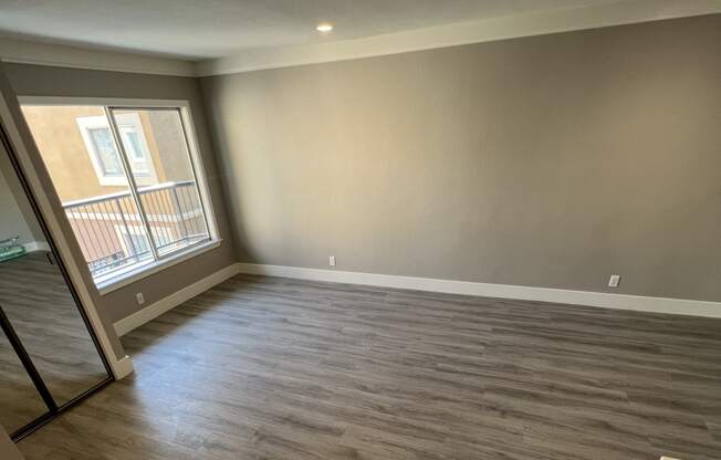 View into living room with wood look flooring, recessed lighting, and well lit almost floor to ceiling window