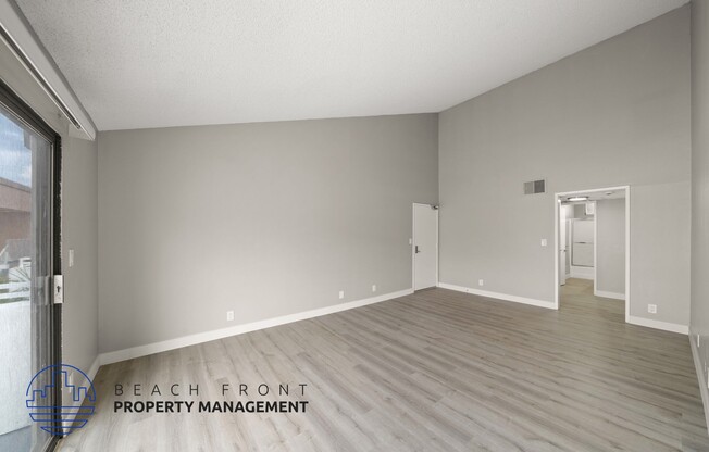 the spacious living room with wood flooring and a large window