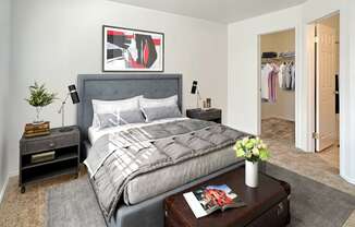 Bridgeside Landing Apartments in Taylorsville, Utah, large double bed with two nightstands, grey bedding, walk-in closet.