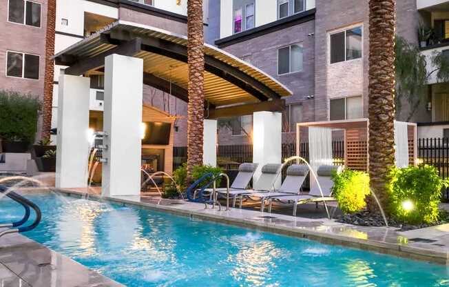 A pool area with a waterfall and lounge chairs.