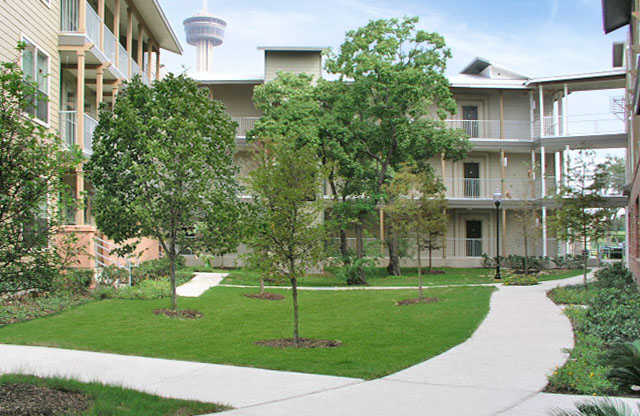 the courtyard of an apartment building with trees and a sidewalk