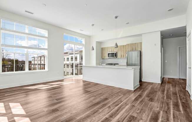 A spacious kitchen with wooden flooring and a large window.