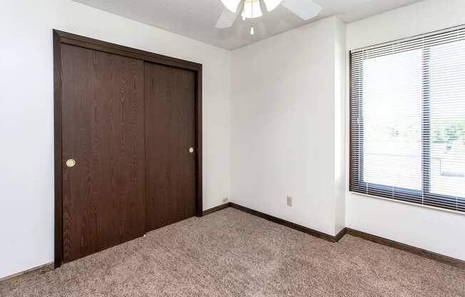 an empty bedroom with a closet and a window