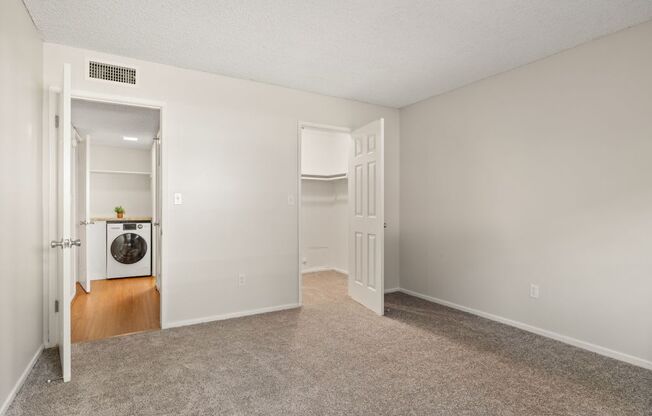 a bedroom with a laundry room and a door to the bathroom