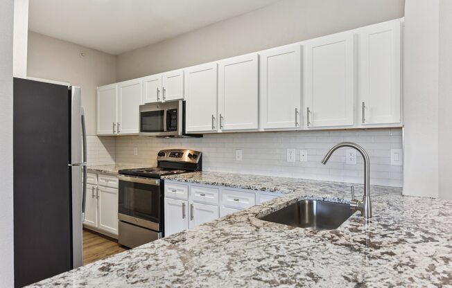 A kitchen with granite countertops and white cabinets.