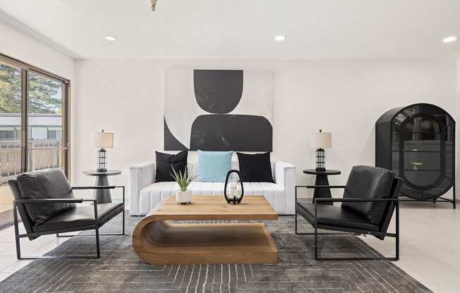 A modern living room with black and white decor and a large abstract painting on the wall.