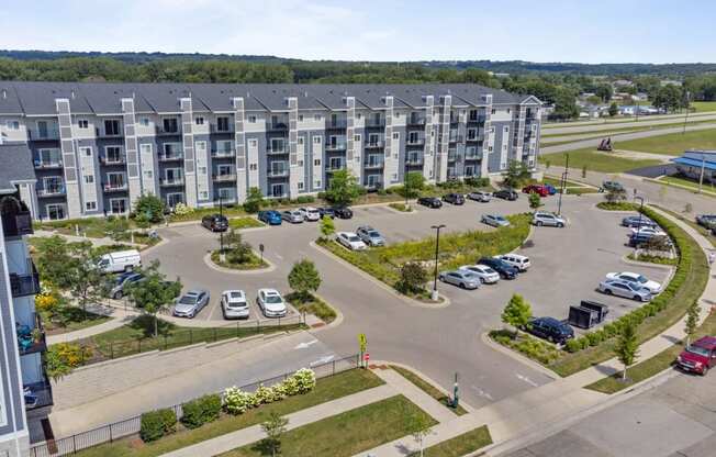 an aerial view of an apartment complex with parking lot and cars