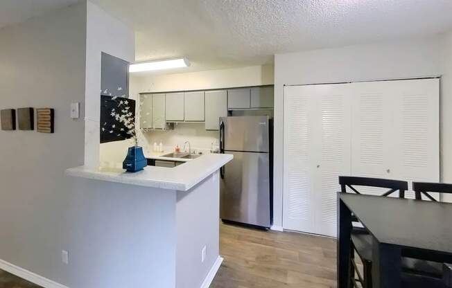 A kitchen with a white counter and a refrigerator.