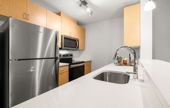 A kitchen with a stainless steel refrigerator, microwave, and sink.