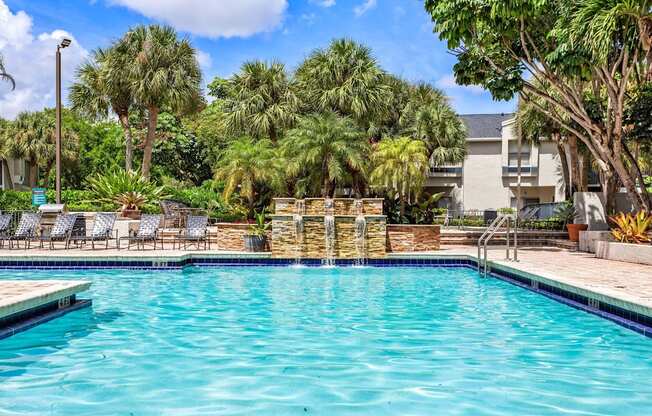 a swimming pool with palm trees and a building in the background at Waterford Park Apartment Homes, LLC, Lauderhill, FL