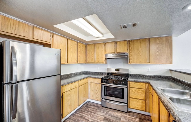 Apartments for Rent in West Las Vegas, NV - Portola Del Sol - Kitchen with Stainless-Steel Appliances, Spacious Countertops, Wood-Style Flooring, and Wooden Cabinets