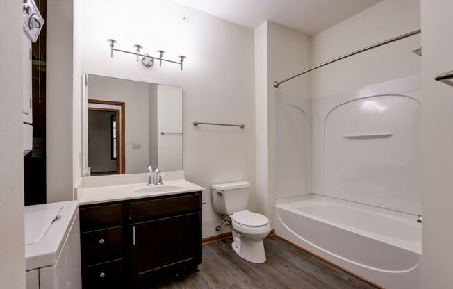 a bathroom with a tub sink and toilet and a mirror