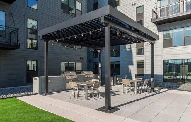 a patio with tables and chairs and a pergola in front of a building