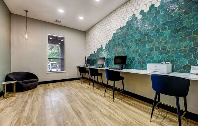 an office with desks and chairs and a wall with green tiles