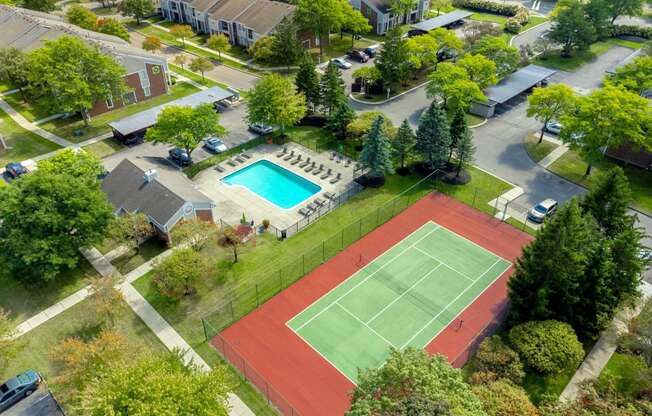 an aerial view of a tennis court and a swimming pool in a neighborhood with houses