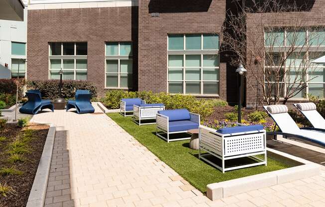an outdoor lounge area with chairs and tables in front of a building