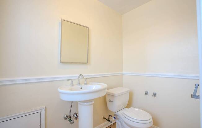 A bathroom with a toilet, sink and mirror.