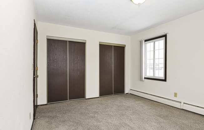 an empty room with a window and two closet doors. Fridley, MN Georgetown on the River Apartments