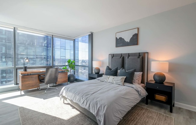 a bedroom with a bed and a desk with a large window