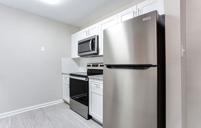 a kitchen with white cabinets and stainless steel appliances