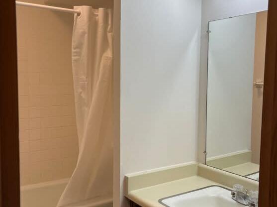 A white toilet is in a small bathroom with a sink and mirror.