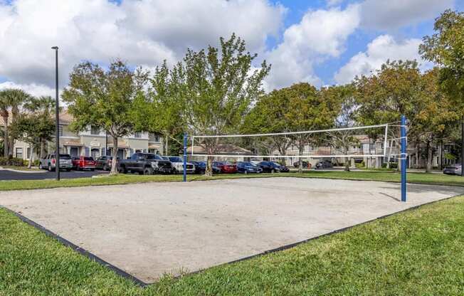 A volleyball net is set up in the middle of a sandy court.