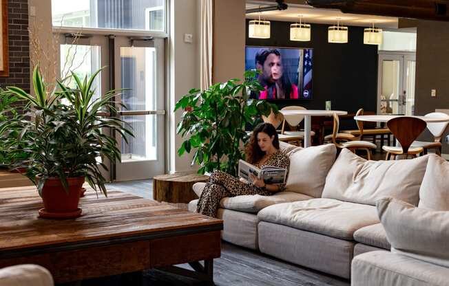 a woman sitting on a couch in a living room with a tv in the background at Bakery Living in Pittsburgh, PA 15206