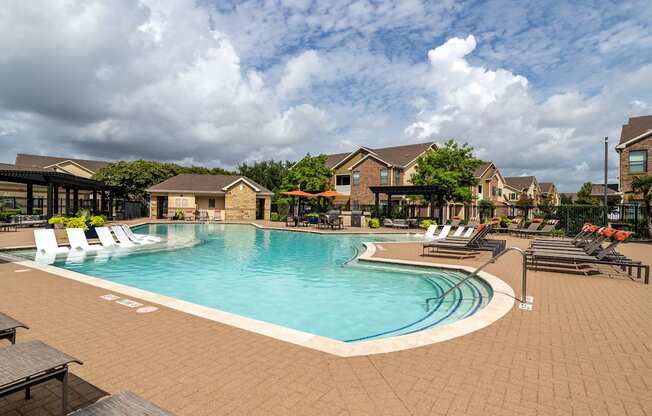 A large outdoor swimming pool surrounded by lounge chairs and umbrellas.