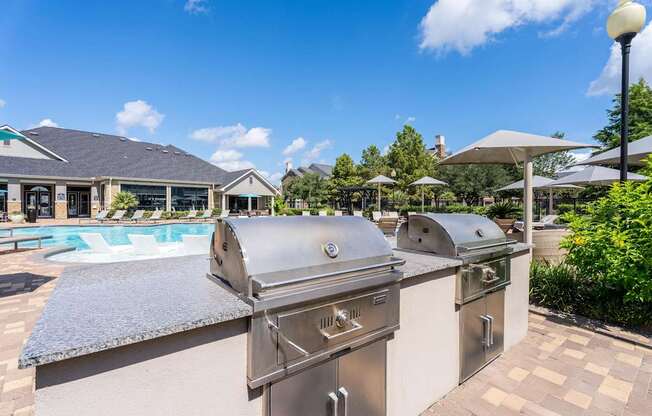A row of stainless steel grills are lined up on a patio.