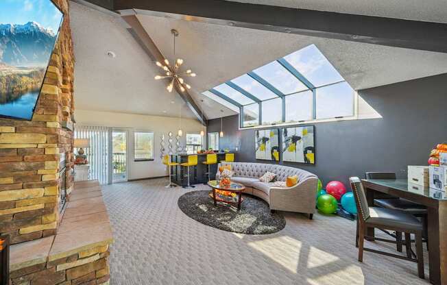 A living room with a stone fireplace and a skylight.
