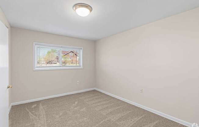 A room with a window showing a house outside.