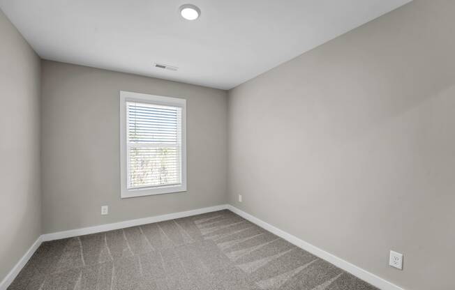 an empty room with carpet and a window