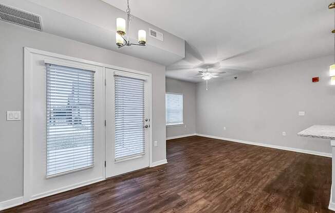 the living room and dining room of an apartment with wood flooring and white walls