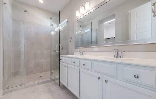 A Luxury Two-Bedroom Homes for Rent in Houston, TX - East Heights - Bathroom with Double Vanity Sink, Shower, White Cabinets, and Mirror.