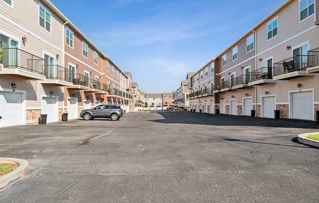 A car is parked in a parking lot in front of apartment buildings.