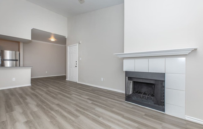 a living room with a fireplace and a kitchen in the background